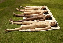Four nude girls sunbathing together